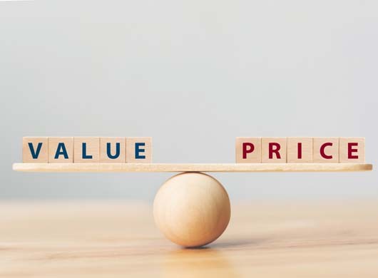 Wooden seesaw scale empty on wooden sphere on wood table with wording VALUE and PRICE balancing